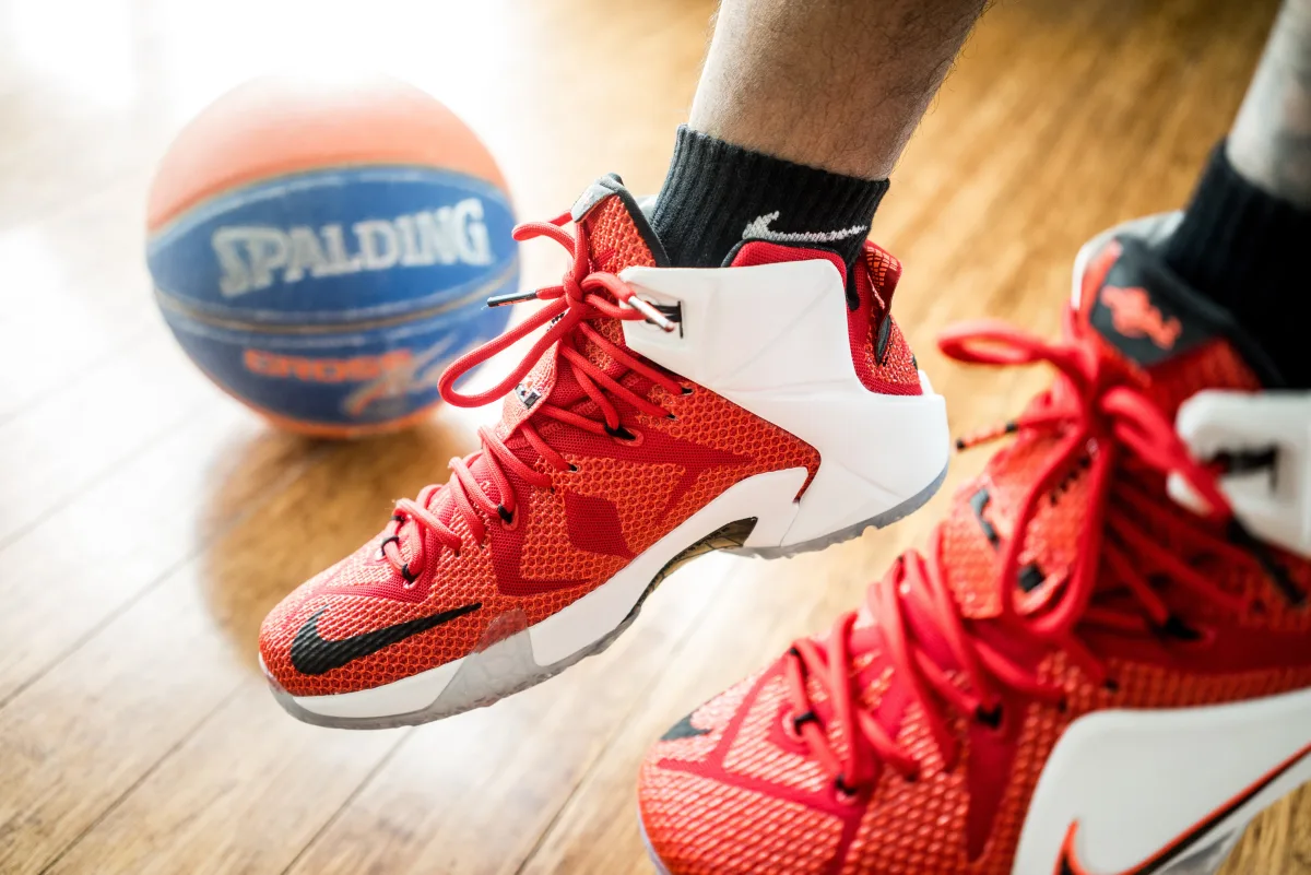 Red basketball sneakers with Spalding ball on wooden floor