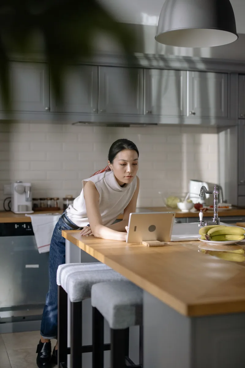 Woman in kitchen using tablet to browse YouTube content