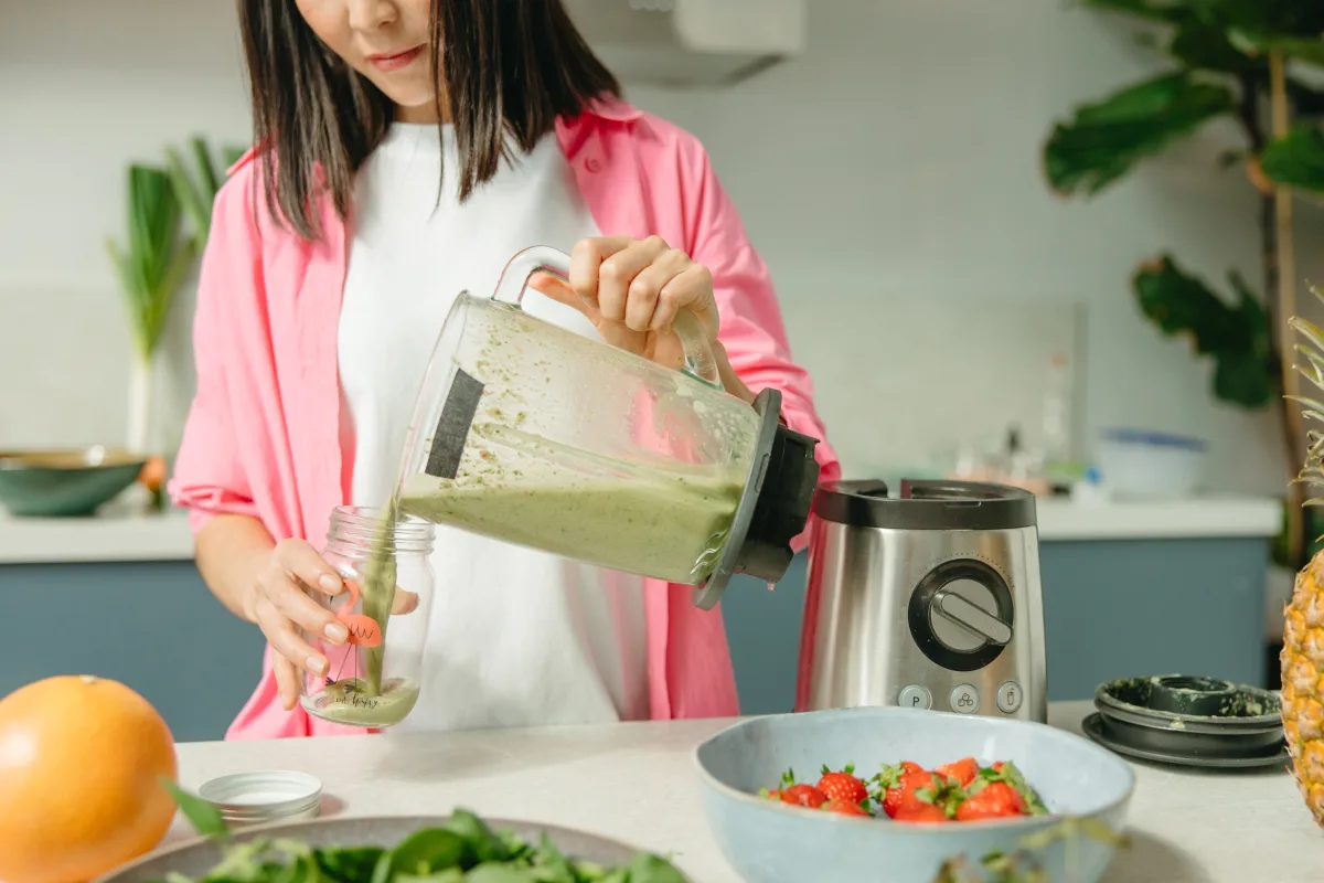 Woman making a green smoothie in a kitchen — NutriBullet six-blade blending