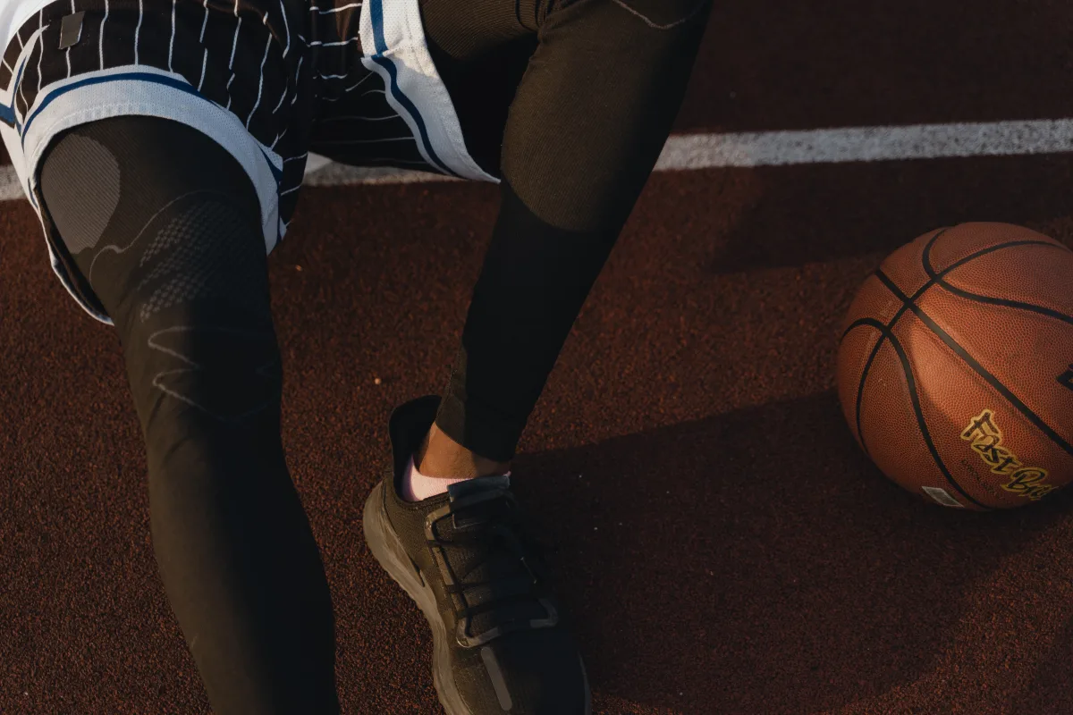 Basketball player resting on outdoor court with ball