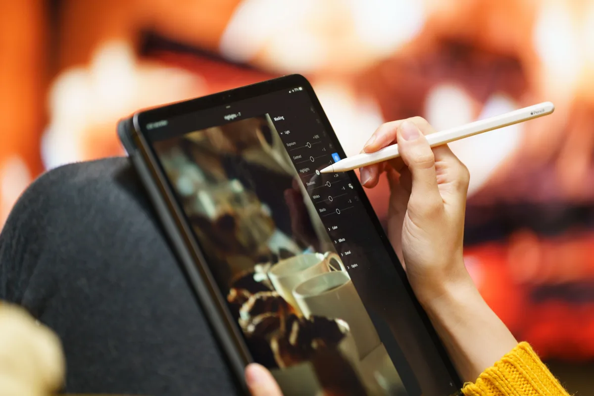 Person using a stylus to draw on a tablet at home, illustrating creative/productivity use
