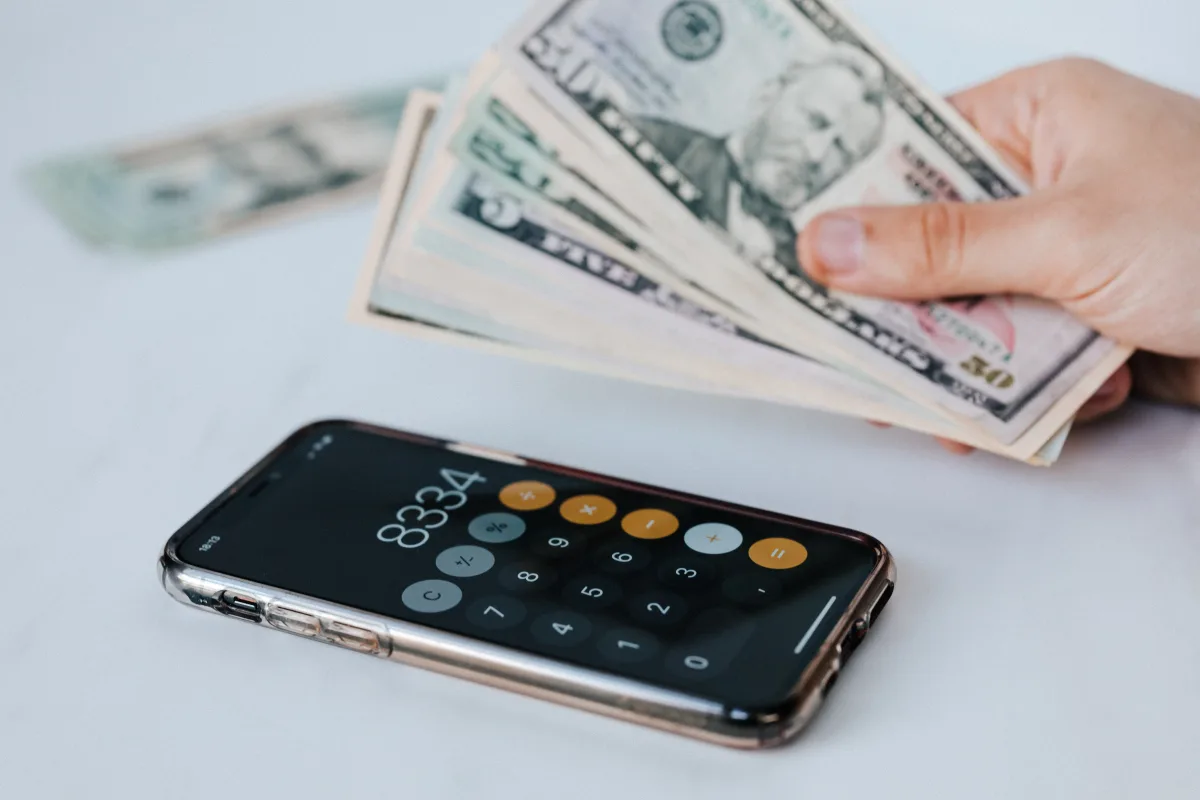 Smartphone calculator screen with dollar bills — zero-based budgeting concept