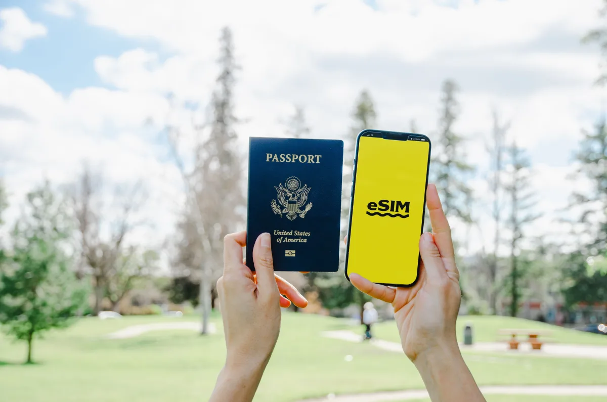 Hands holding passport and smartphone with eSIM app open