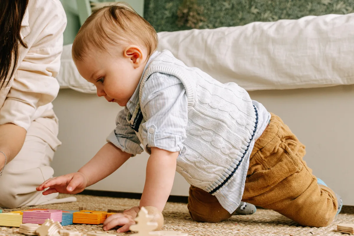 Baby boy playing with colorful wooden blocks on floor — best STEM toys for toddlers and preschoolers 2026