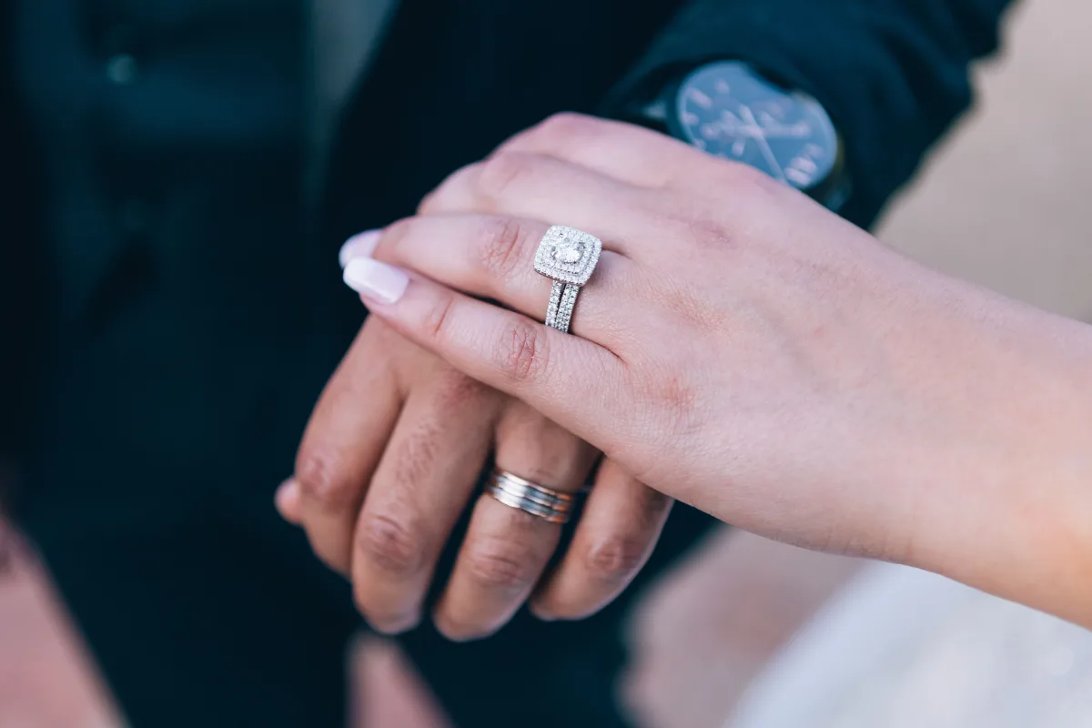Couple's hands showing diamond engagement ring and wedding band together