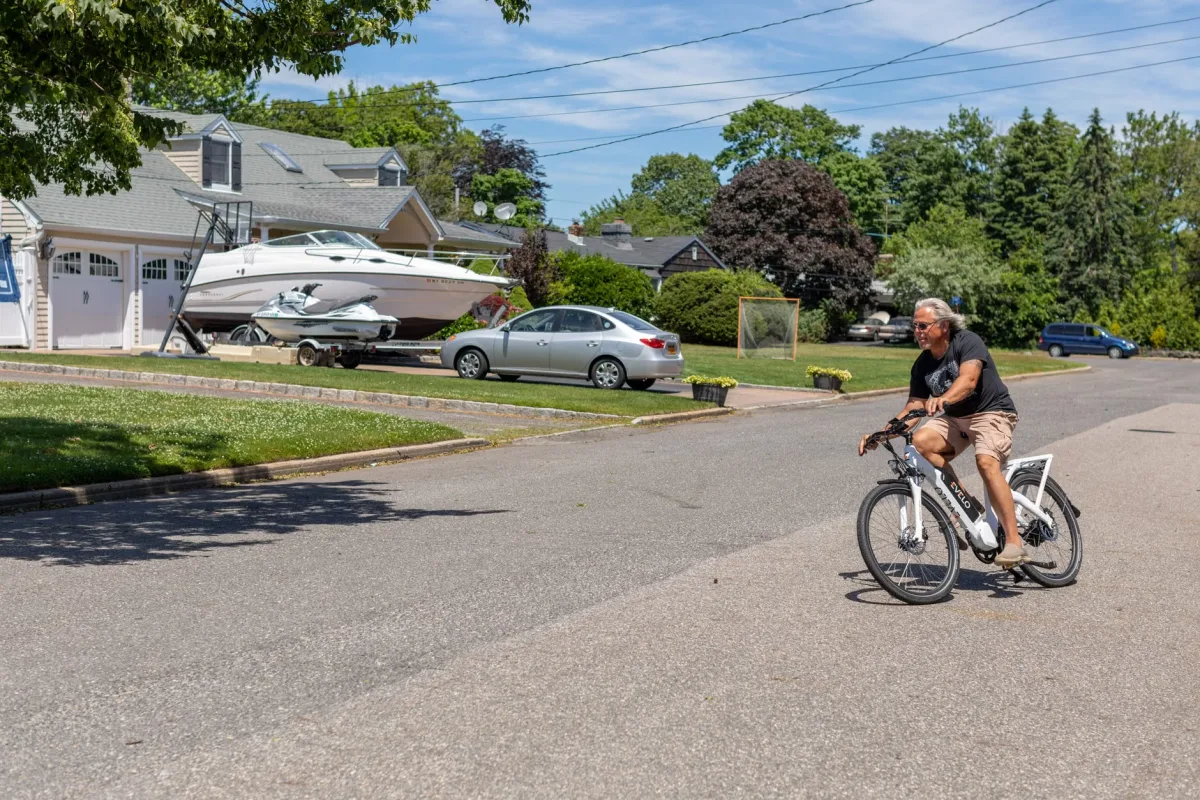 Rider on an electric bike cruising a sunny suburban street