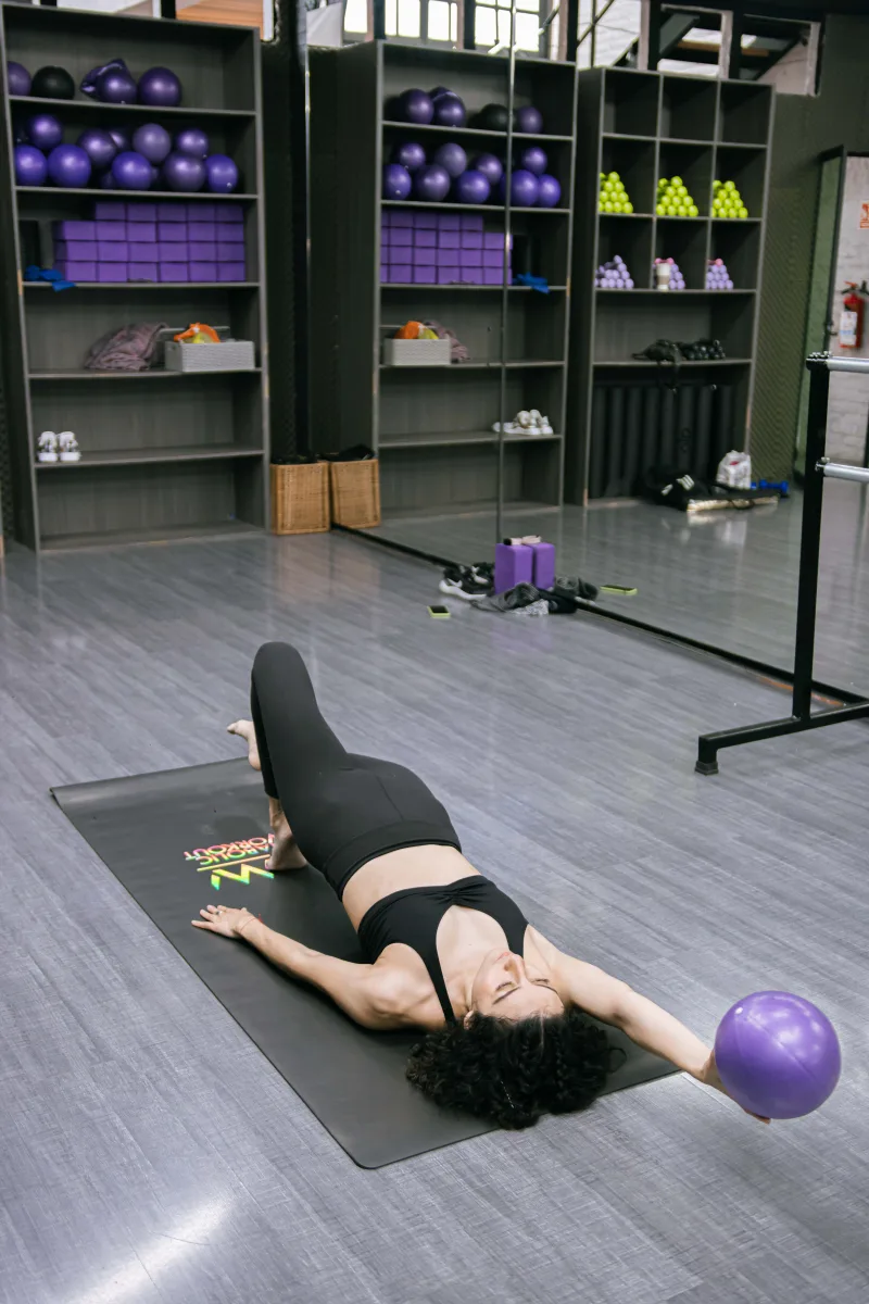 Woman exercising with Pilates ball on a mat in a gym