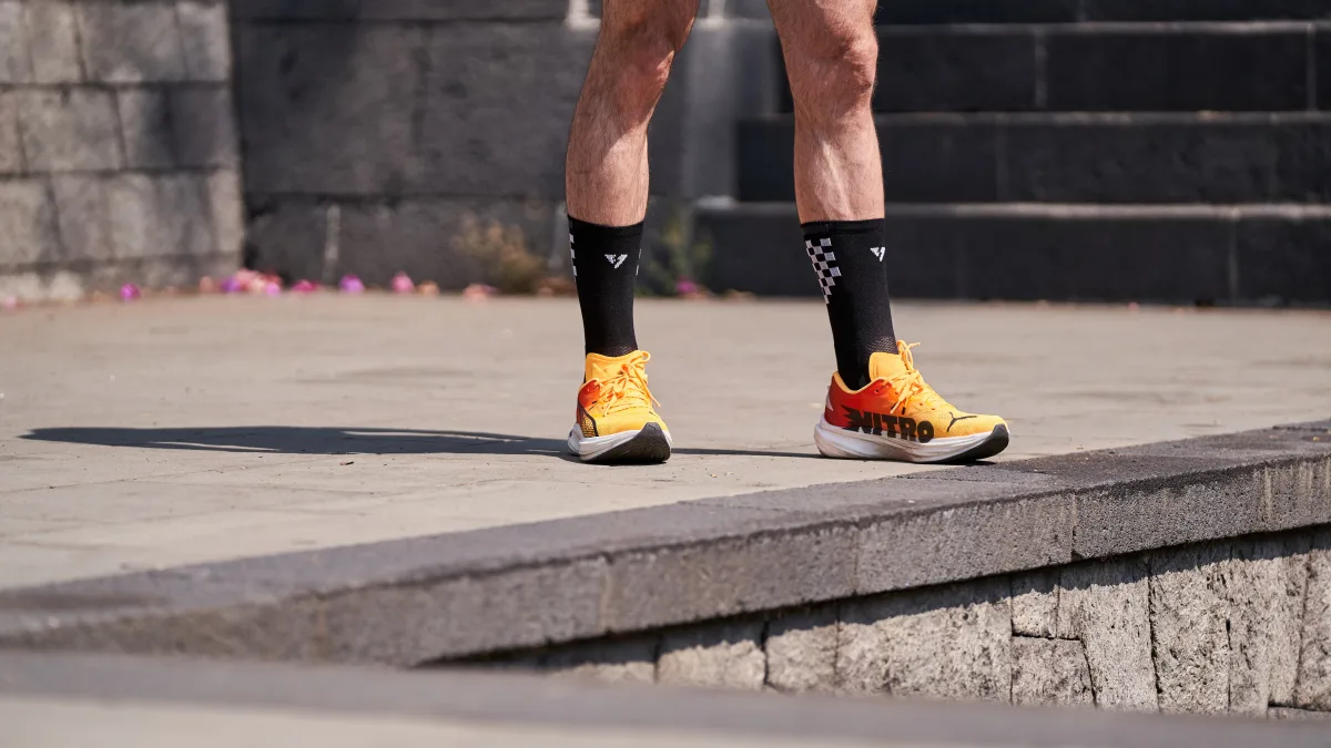 Close-up of a runner's legs wearing orange running shoes on pavement