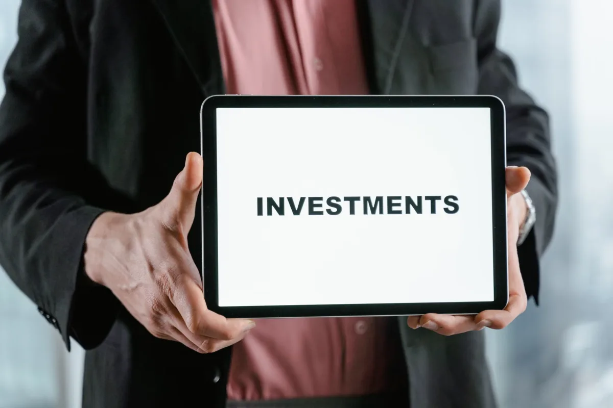 Businessman in suit holding tablet displaying the word Investments
