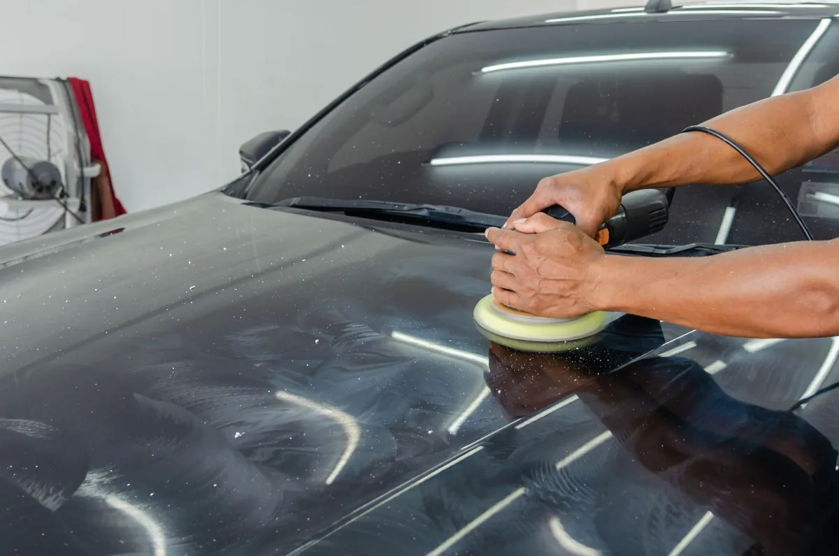 Buffing machine on black car (indoor workshop)
