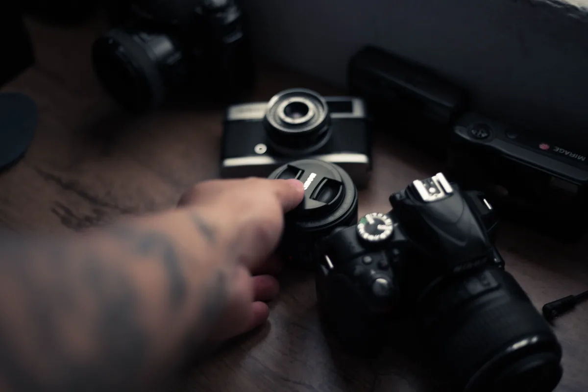 Photographer selecting a camera lens from equipment laid out on table
