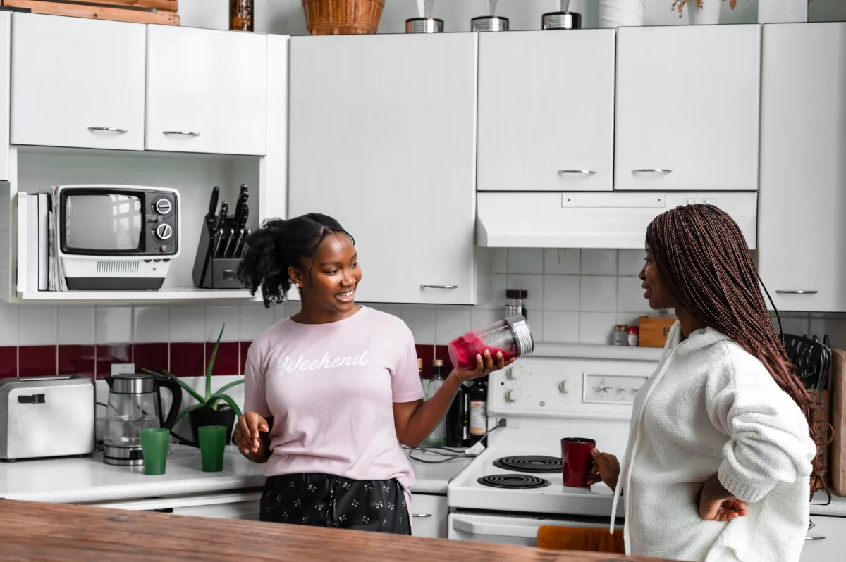 Two women in a kitchen making a hot blended soup using a countertop blender