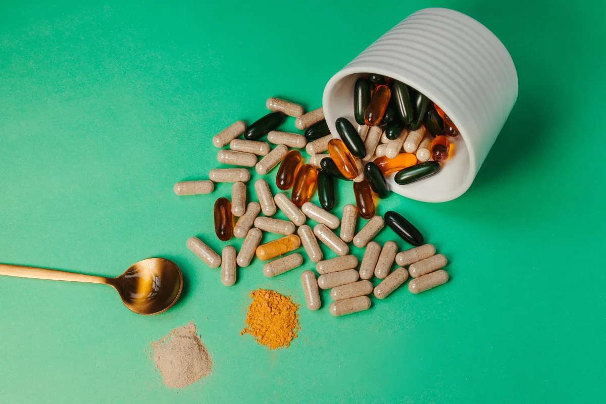 Assorted supplement capsules and powder on green background