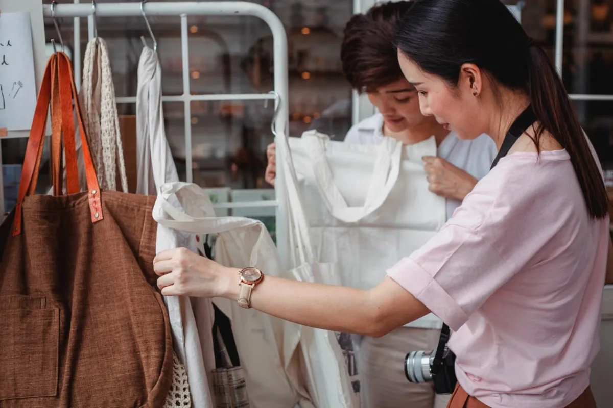 Young woman browsing eco-friendly cotton bags in a sustainable fashion boutique