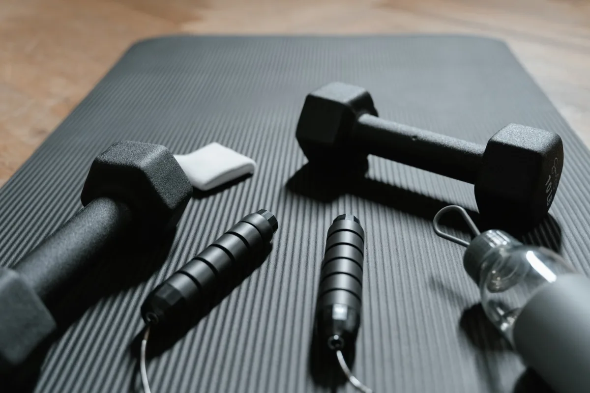 Dumbbells, jump rope, and water bottle on yoga mat