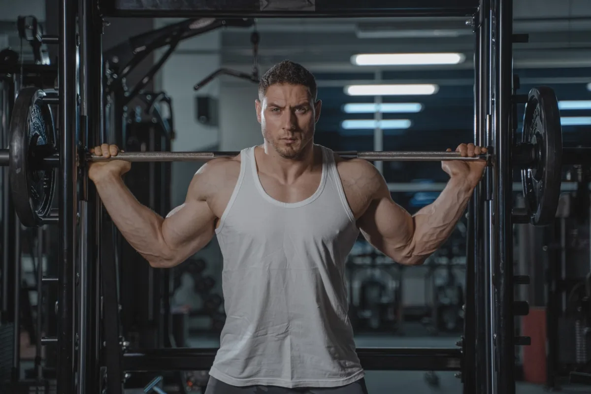 Muscular man in white tank top lifting weights