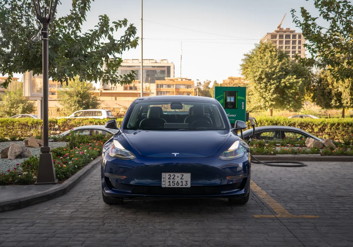 Blue Tesla Model 3 charging at an outdoor station