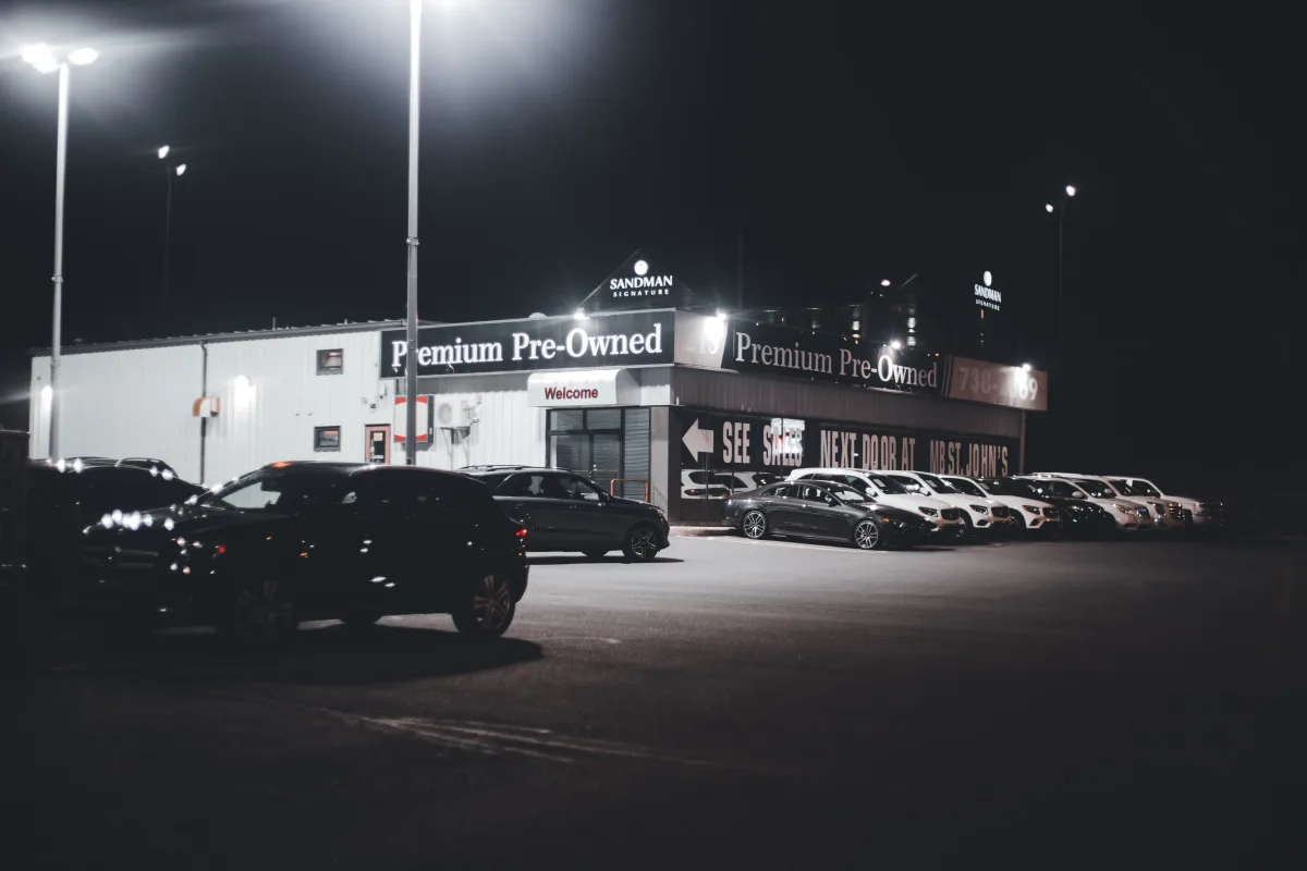 Illuminated used car lot with rows of pre-owned vehicles at night