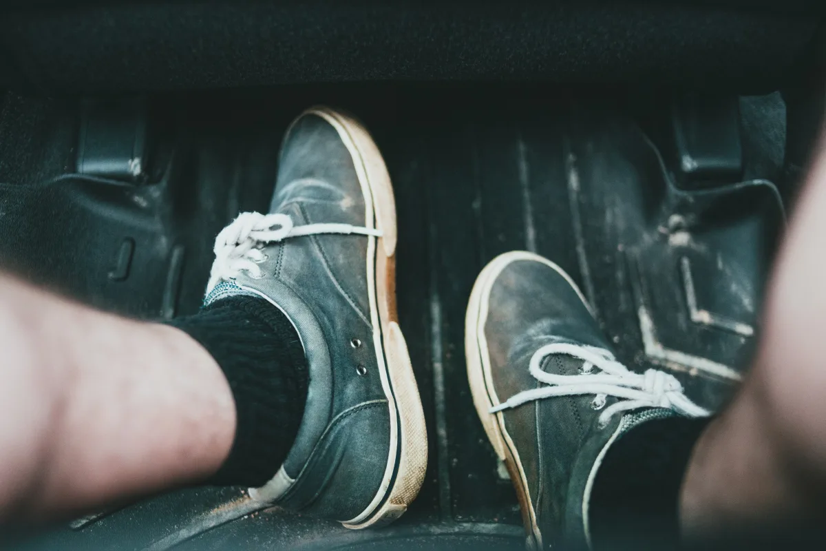 Close-up of sneakers on a car floor mat showing everyday use