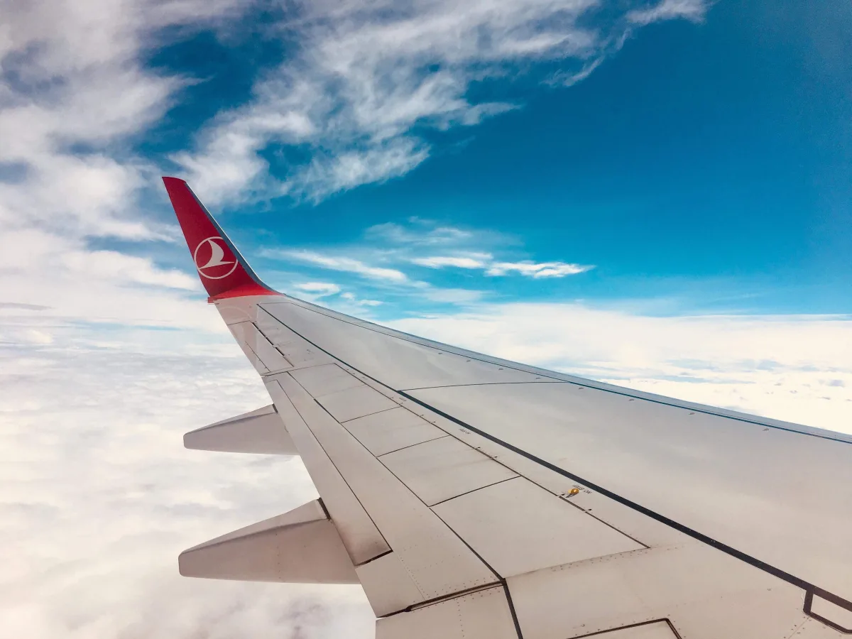 Airplane wing against clear blue sky — flight booking