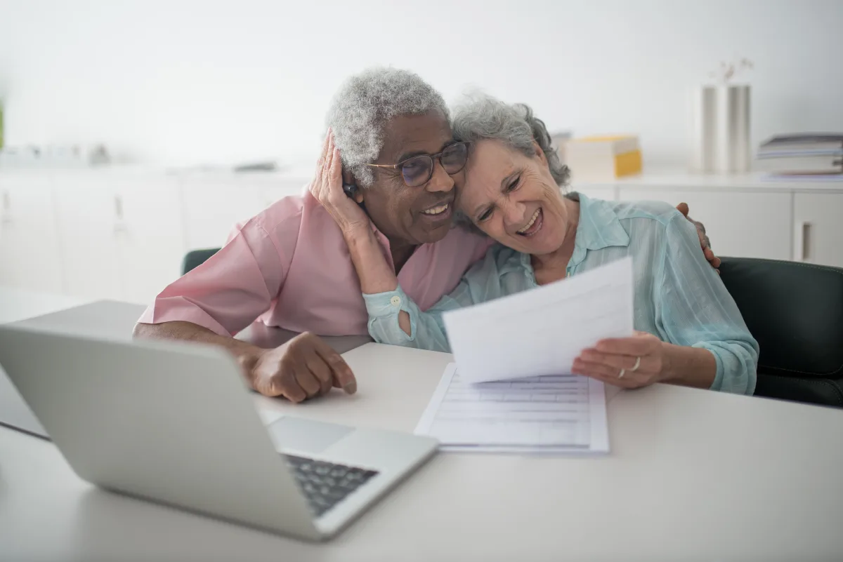 Senior couple reviewing financial documents together with a laptop