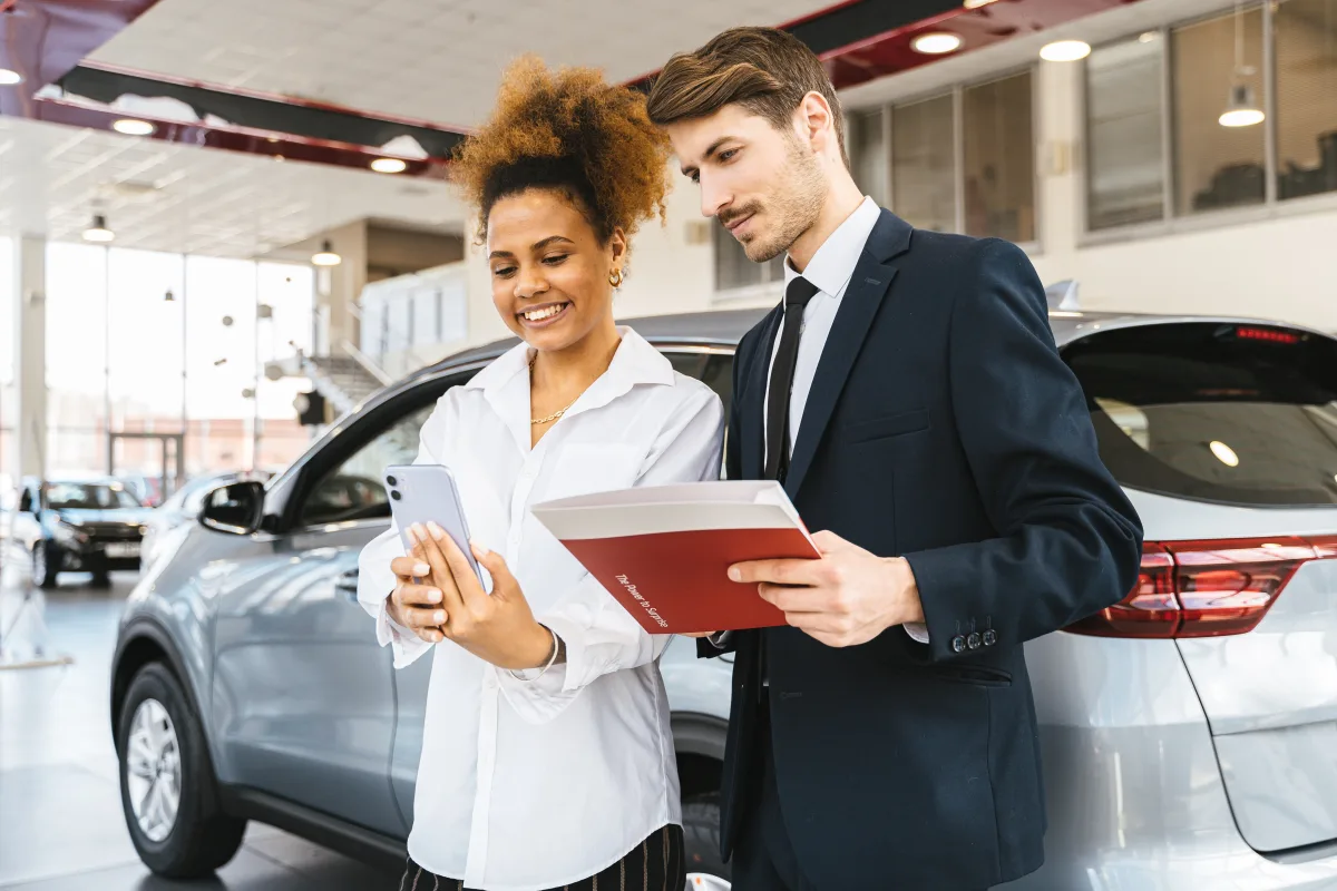 Woman and man reviewing documents at a car dealership negotiation table