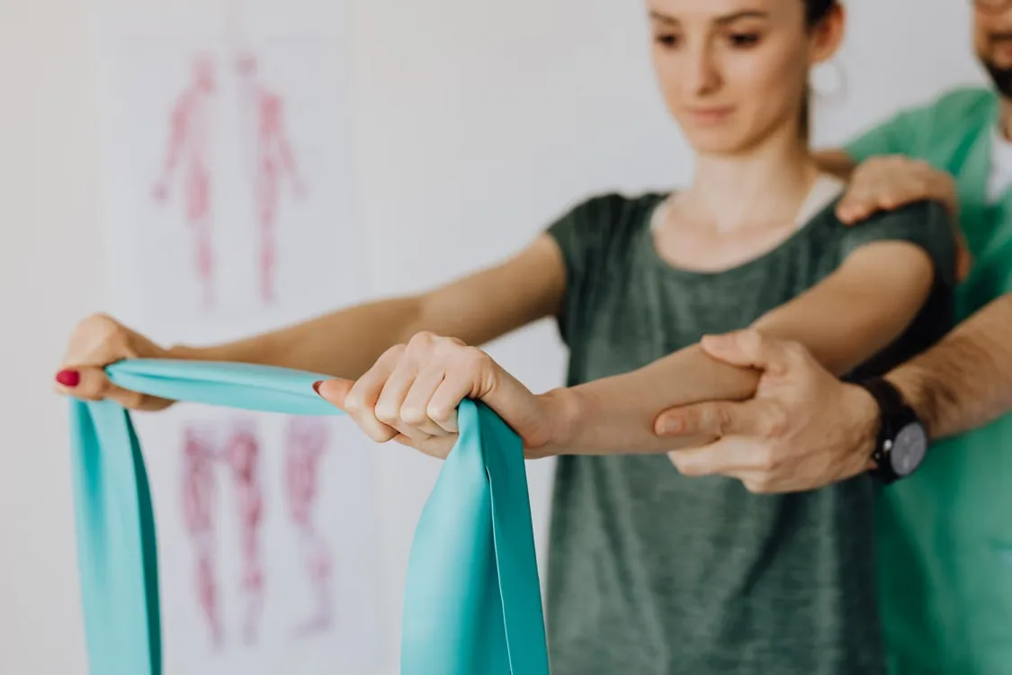 Physical therapist assisting patient with resistance band shoulder rehabilitation