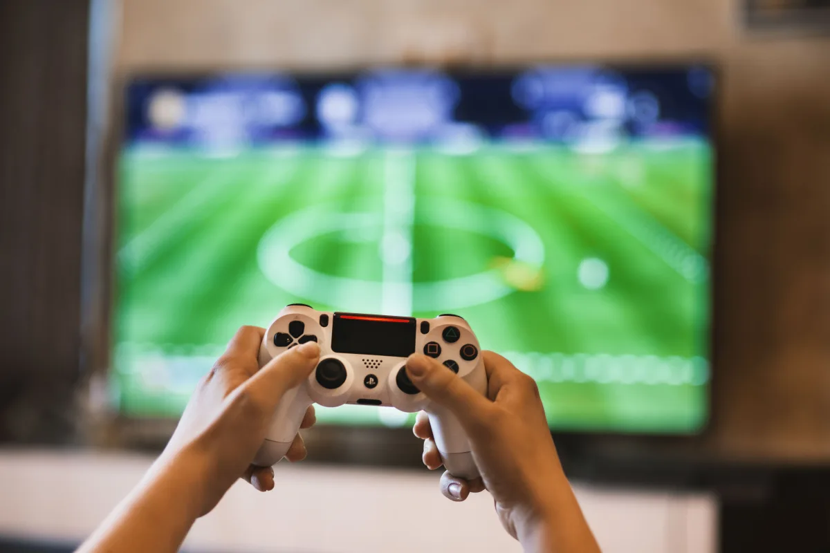 Person holding a PlayStation gamepad while gaming