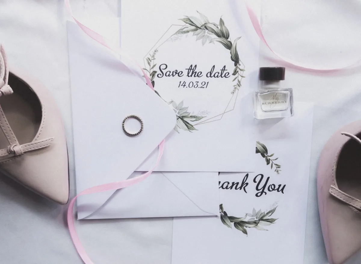 Wedding invitations, ring, perfume, and shoes styled for a chic celebration