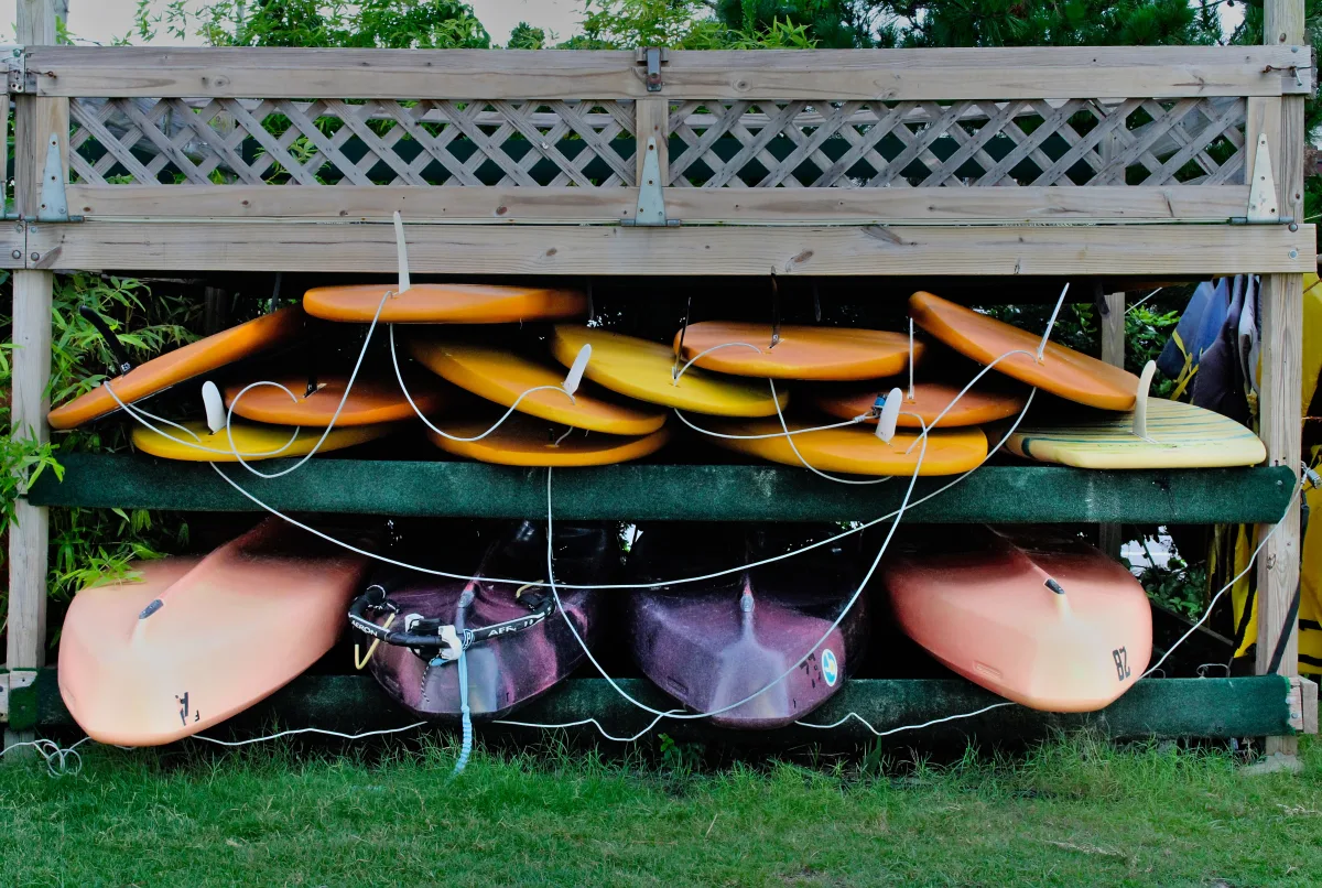 Colorful kayaks and paddleboards stacked outdoors for water sports