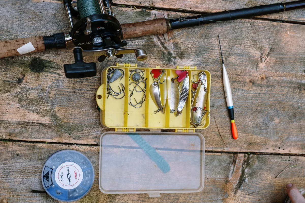 Top-down view of fishing equipment and tackle on rustic wooden surface