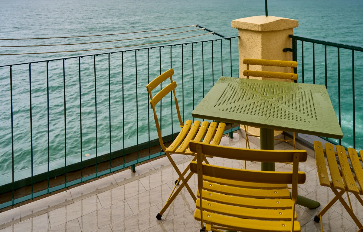 Yellow bistro chairs on seaside balcony — representing cast aluminum durability in coastal settings