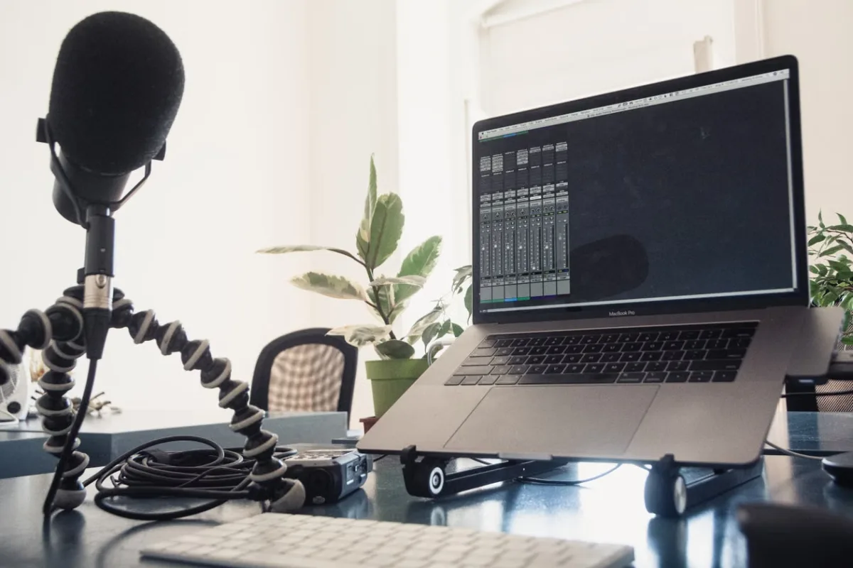 Professional podcast recording setup with laptop and condenser microphone on a studio desk