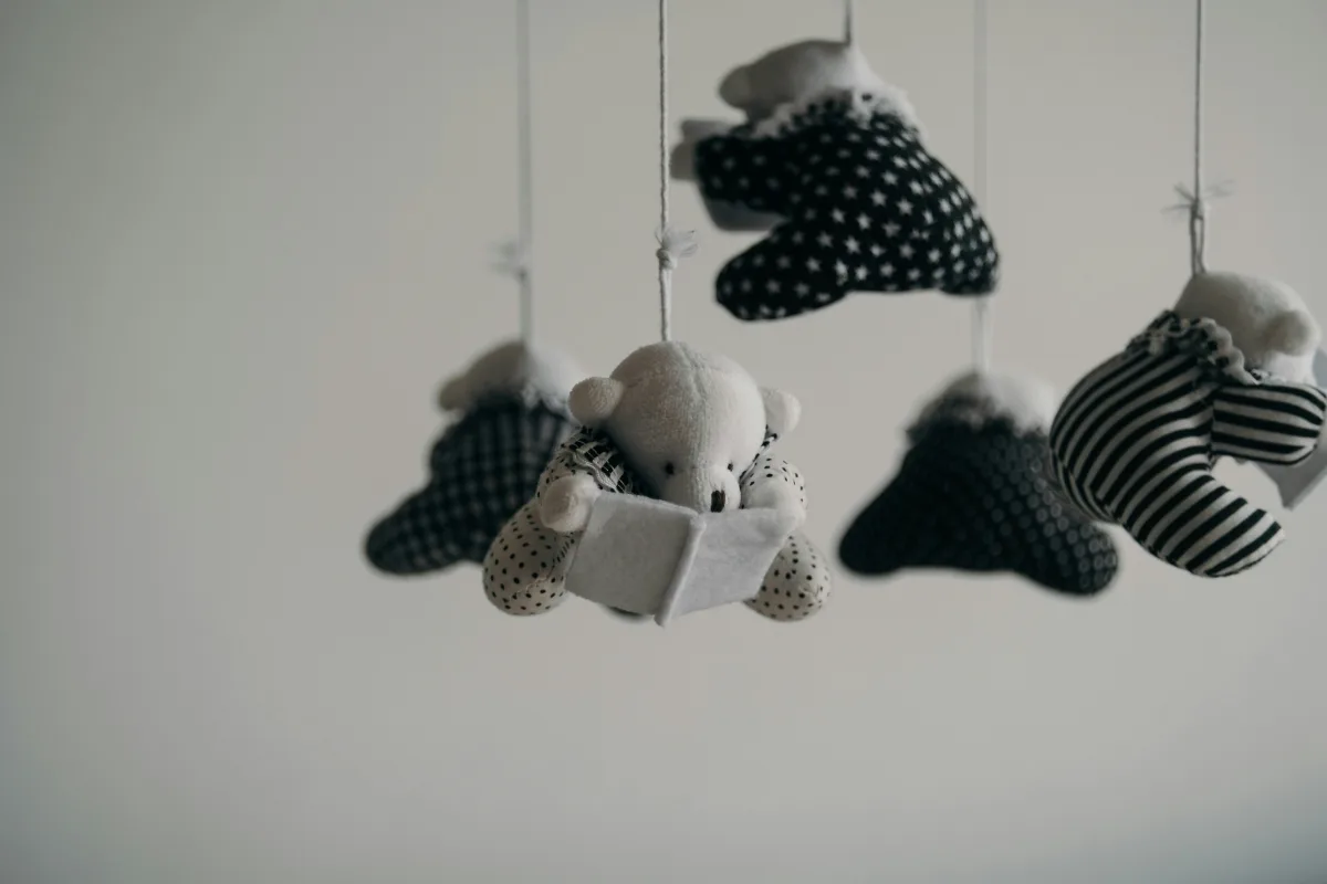 White crib mobile hanging above a baby crib in a minimalist nursery room