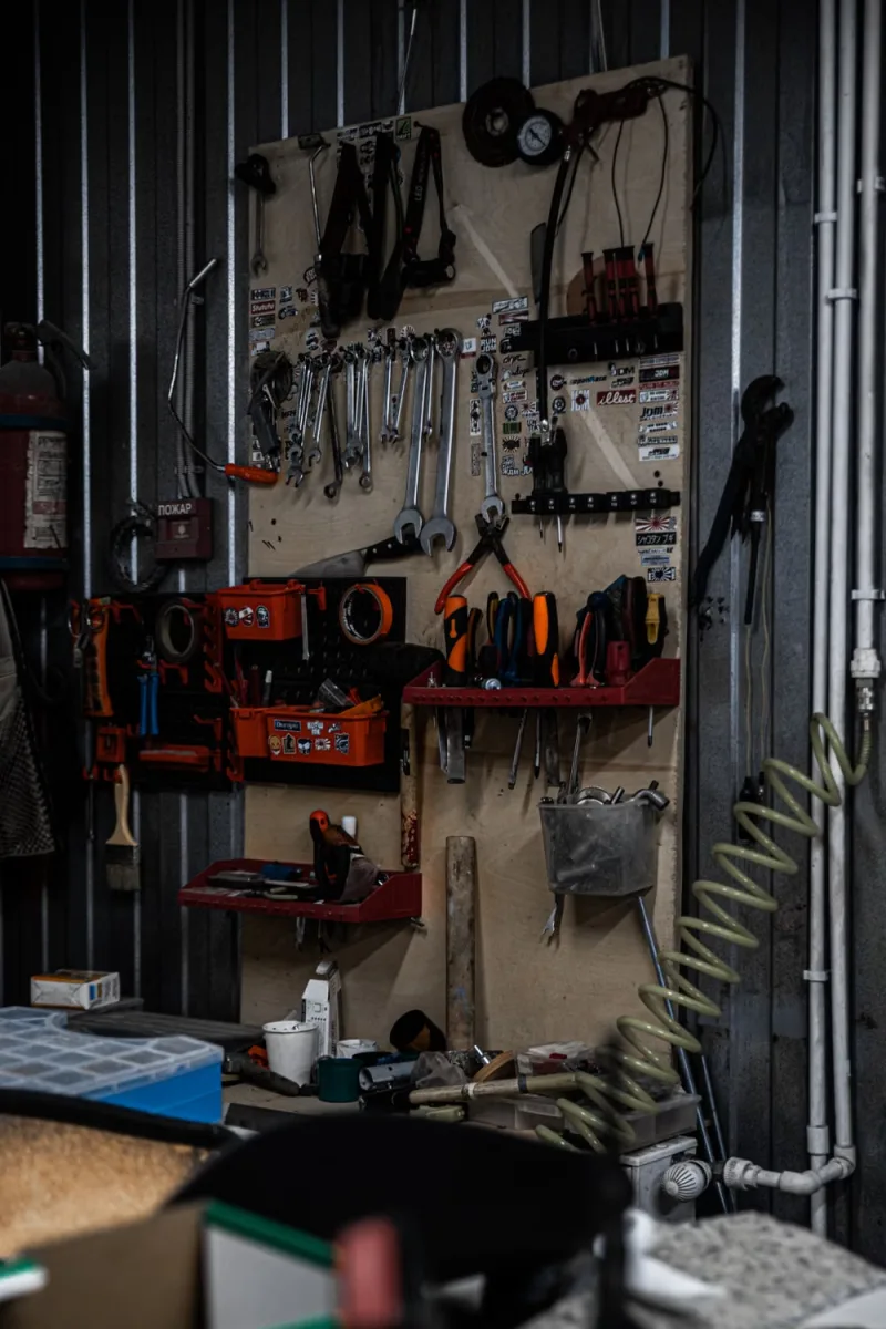 Well-organized garage workshop with tools hanging on a metal wall and stored in cabinets