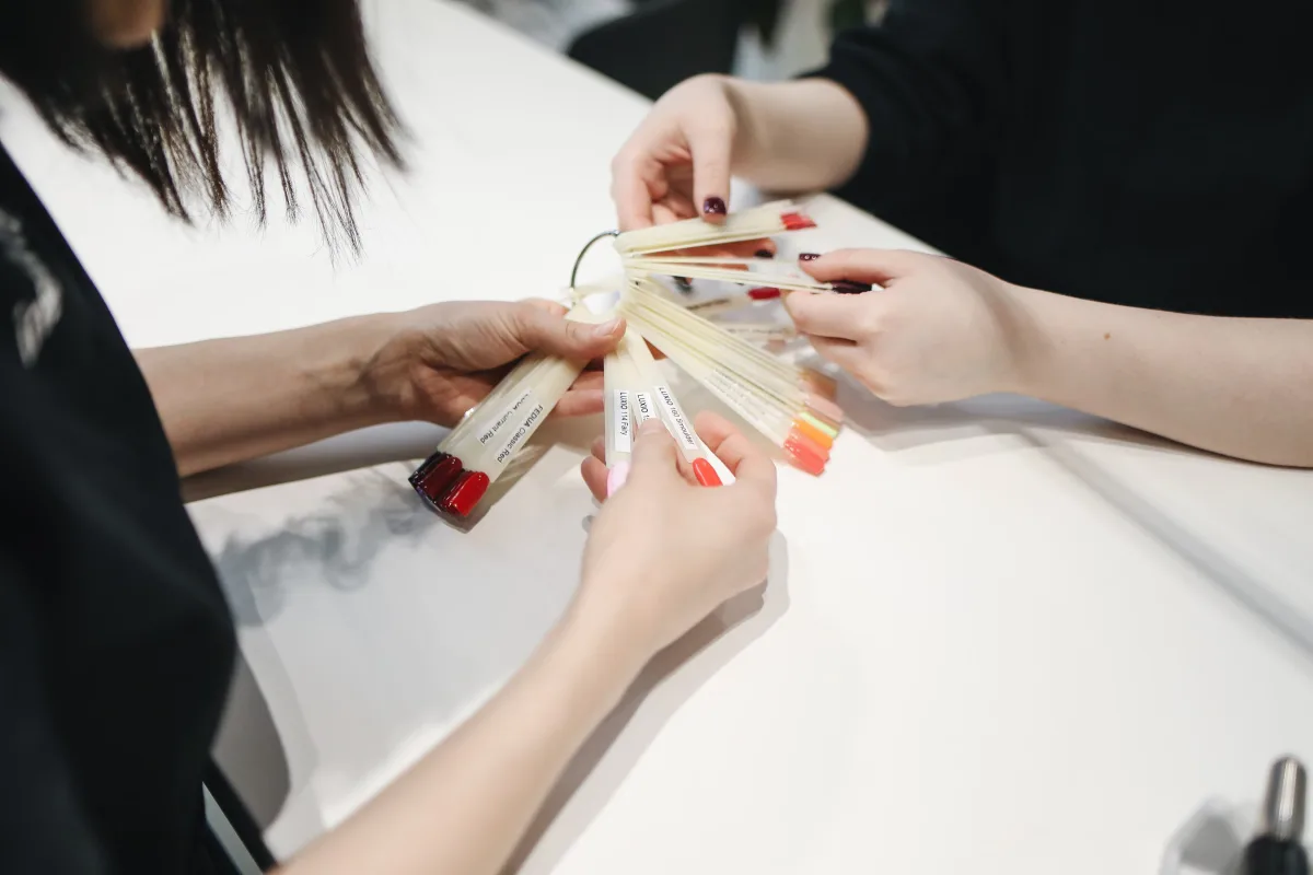 Close-up of hands selecting nail polish colors, illustrating HEMA-free and formula choices