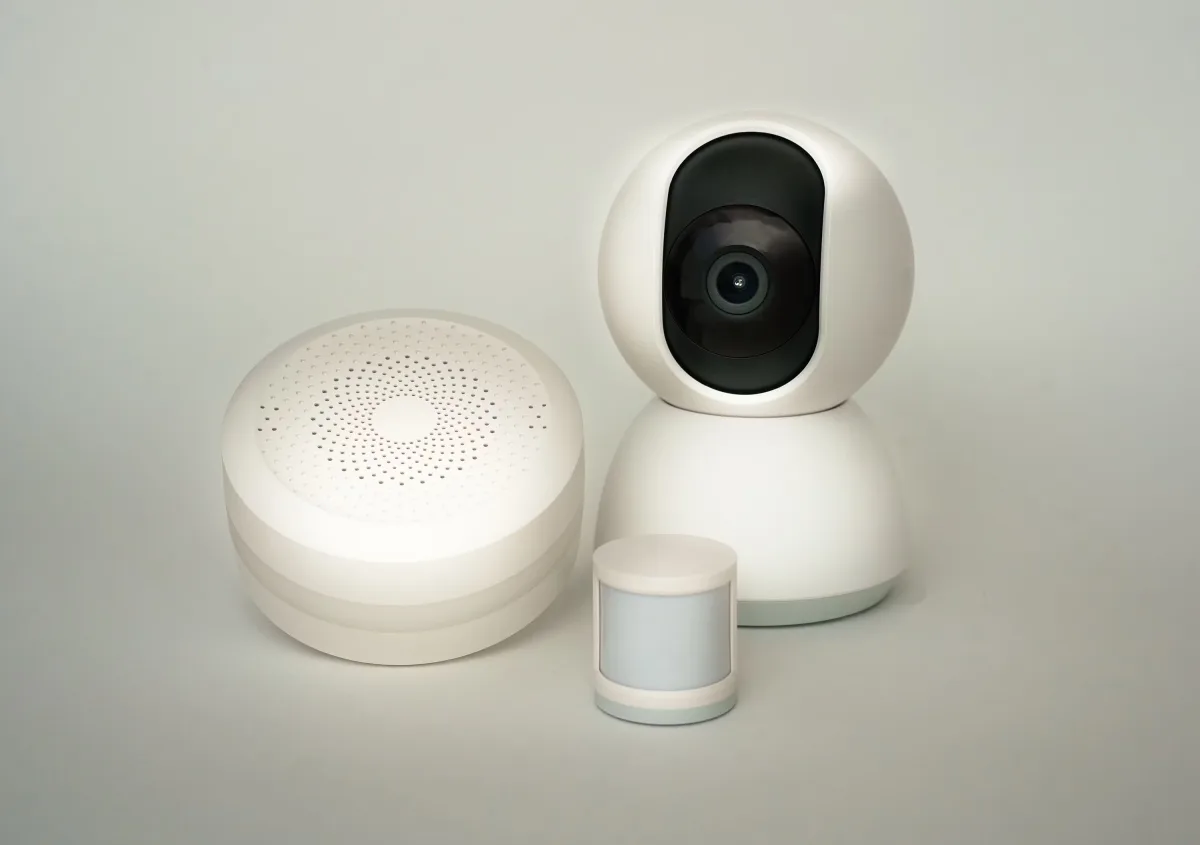 Modern smart home devices including camera and sensors on neutral background — room by room smart home setup guide 2026