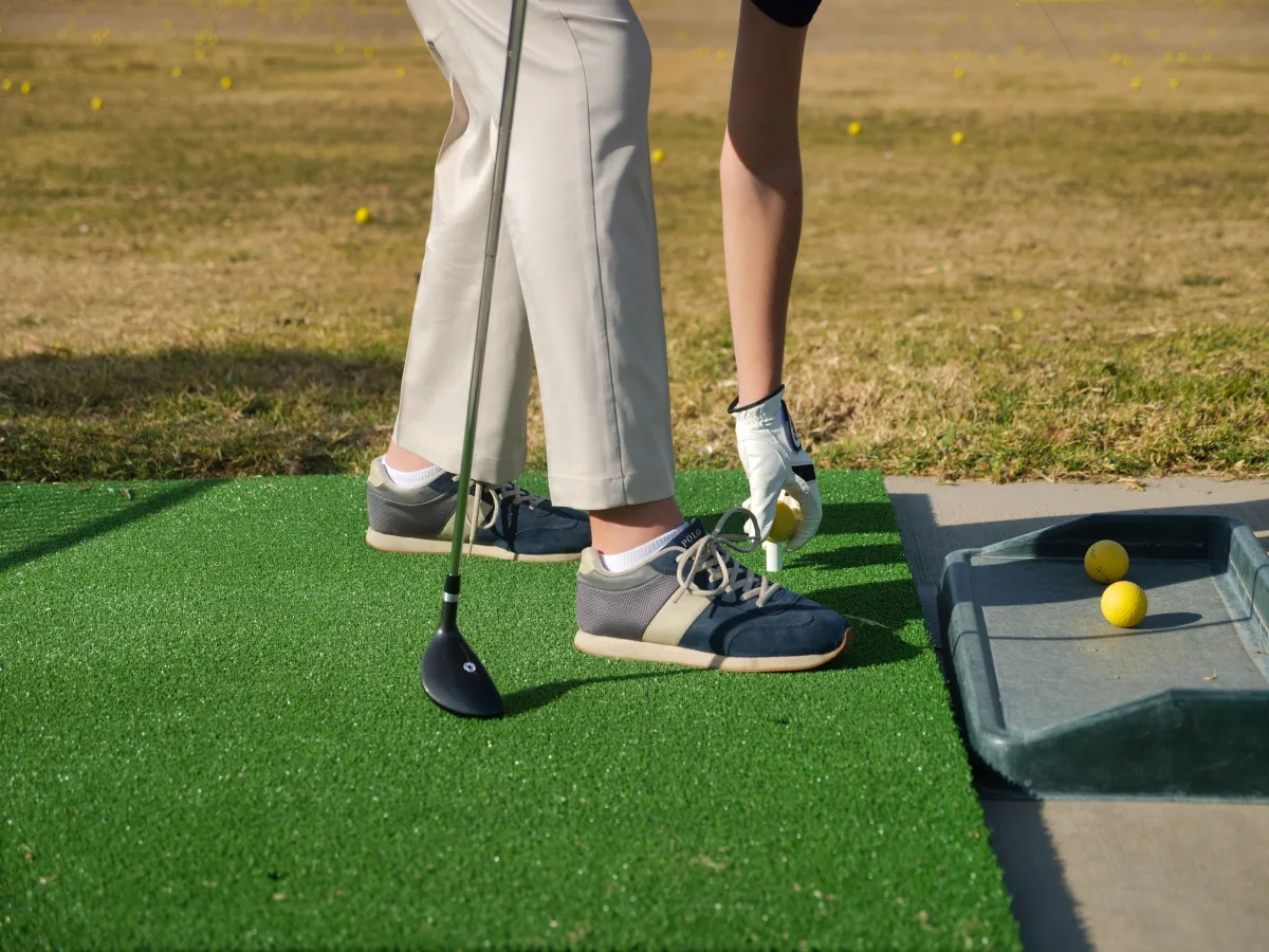 Golfer at driving range comparing equipment brands 2026