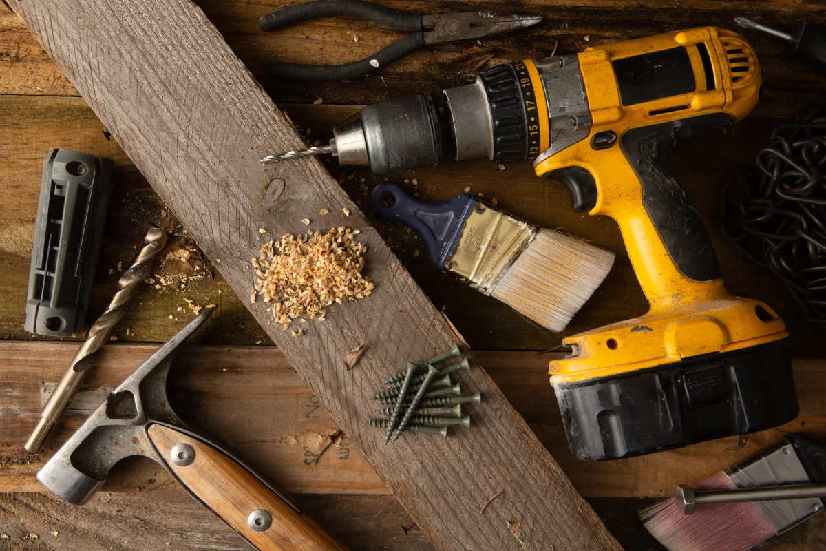 Various tools including a drill and hammer on a wooden workbench