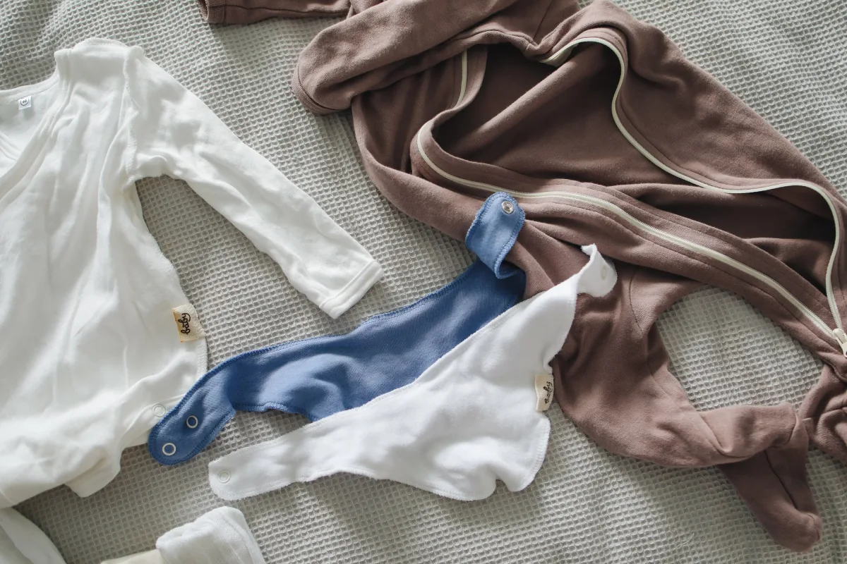 Flat lay of folded baby cotton suits and bibs on a neutral background