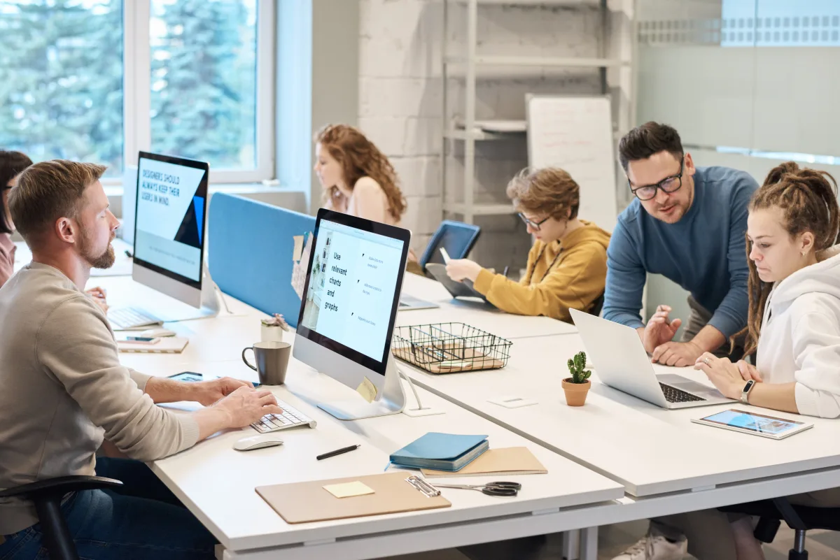 Design team collaborating around a screen reviewing visual assets