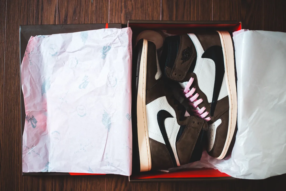 New sneakers in an open cardboard box on a wooden floor