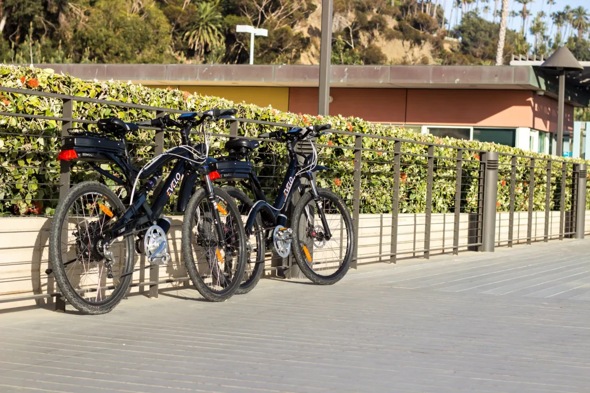 Two electric commuter bikes parked on a sunlit wooden boardwalk