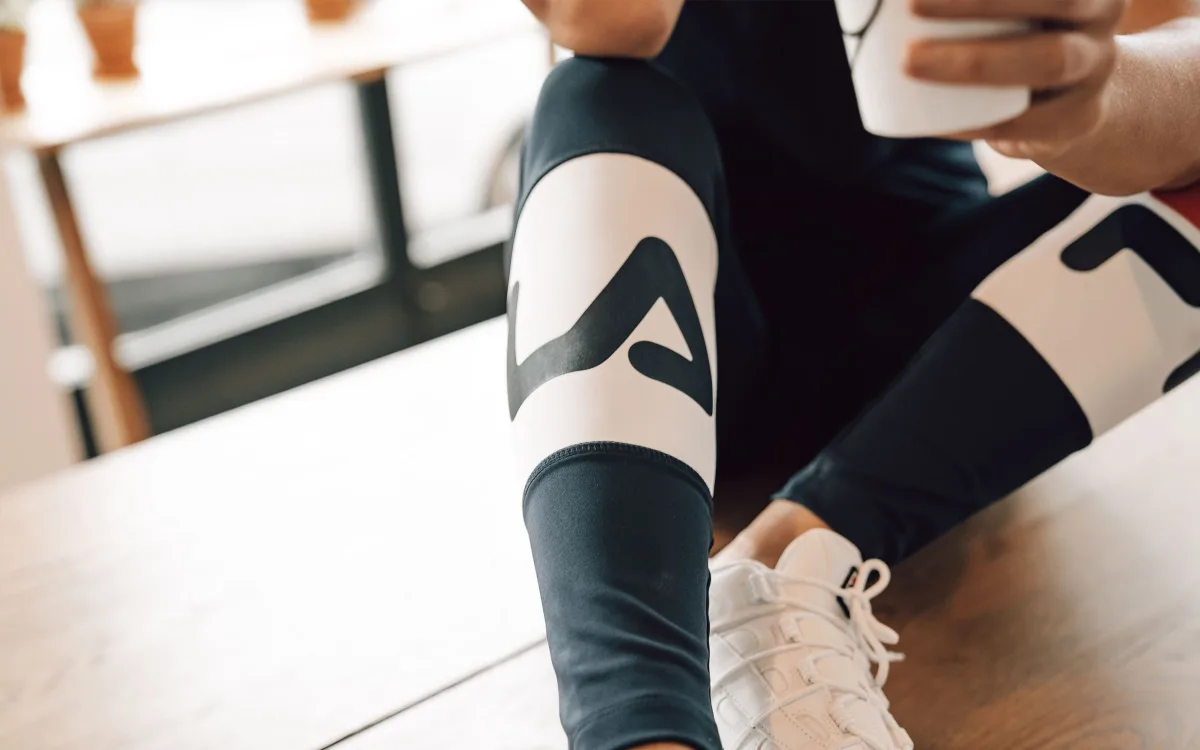 Shopper in black athleisure leggings and sneakers comparing activewear brands on a smartphone