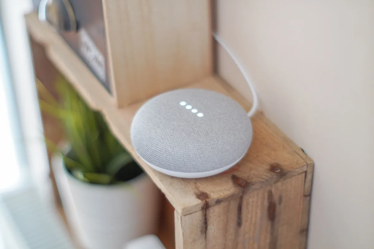 Google Home Mini smart speaker on a wooden shelf — Apple HomeKit and smart speaker ecosystem comparison 2026