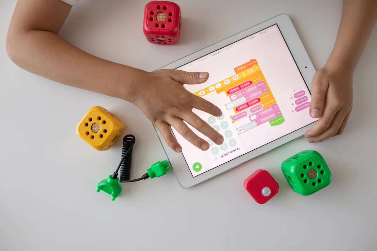 Child using tablet for coding education alongside colorful toy blocks — best educational STEM toys 2026