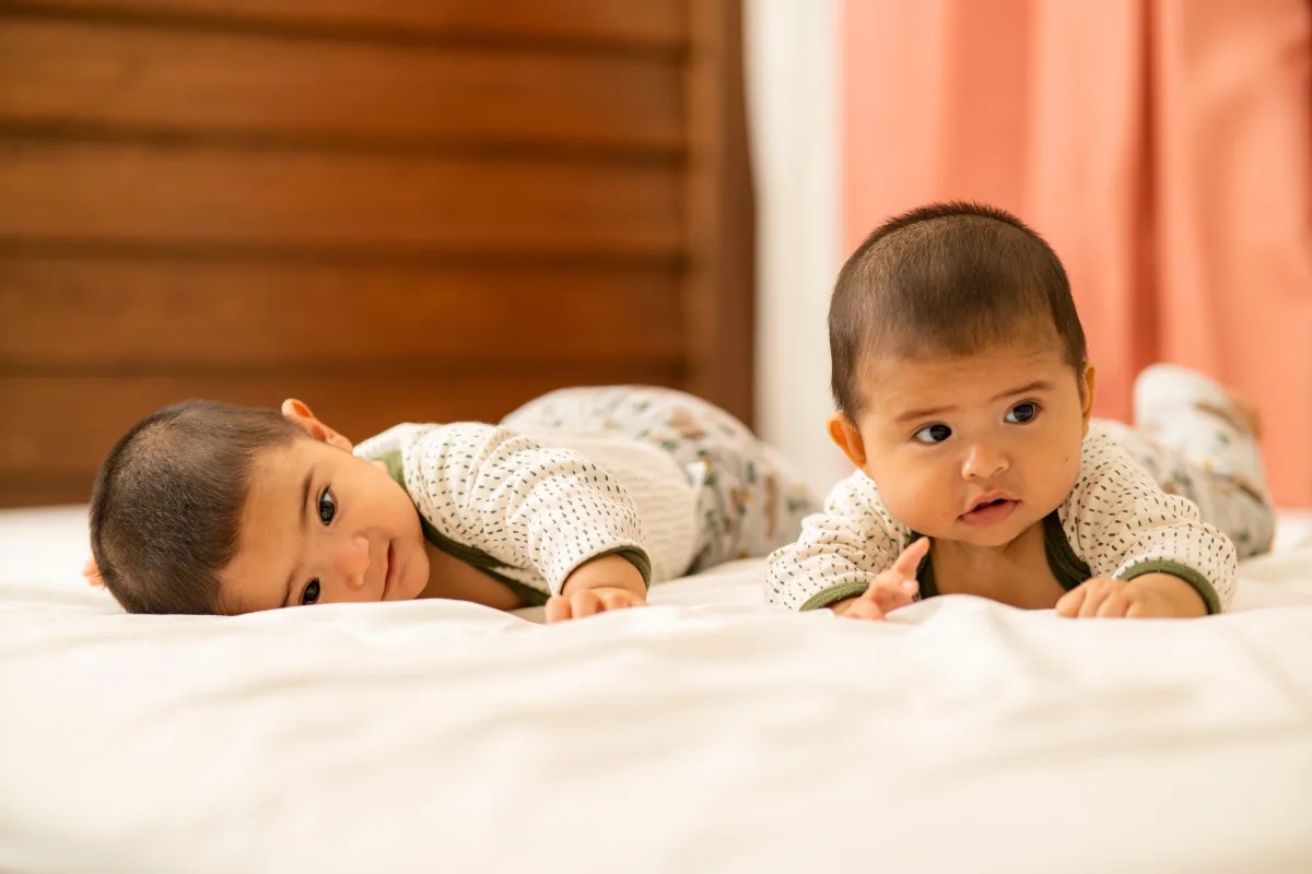 Twin babies lying on a bed in soft cotton outfits
