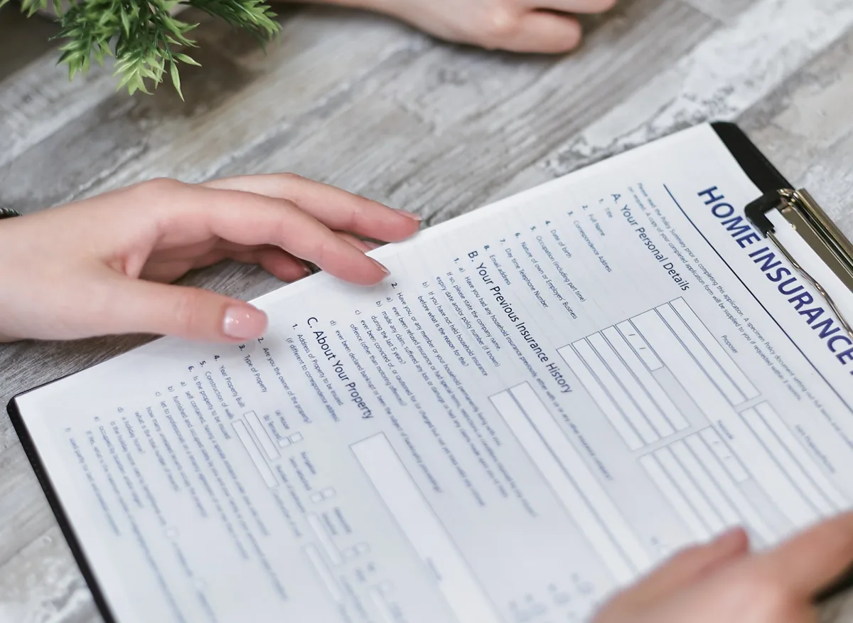 Person holding home insurance document indoors, reviewing personal details