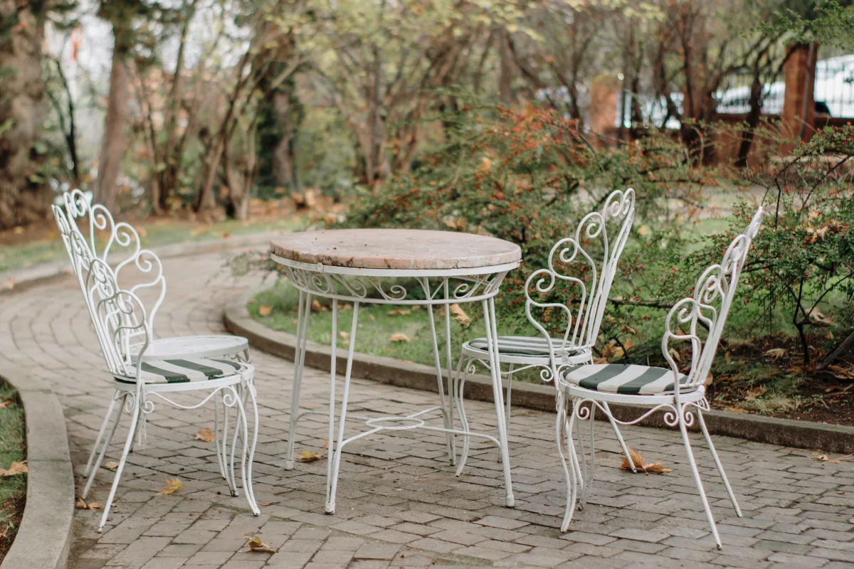 Outdoor café table with iron chairs in park setting — natural material outdoor furniture