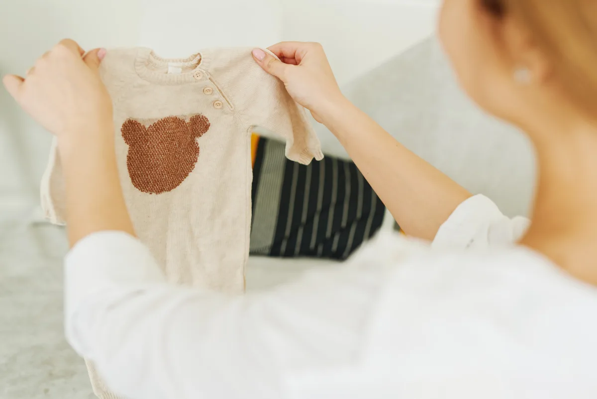 Woman examining a beige organic baby jumper